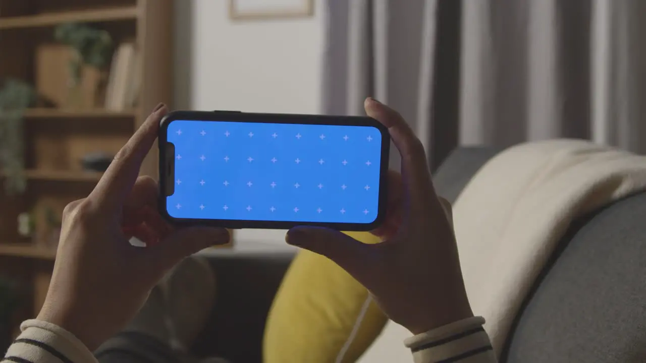 Close Up Of Woman At Home Streaming And Watching Film Onto green screen blue Screen Mobile Phone 