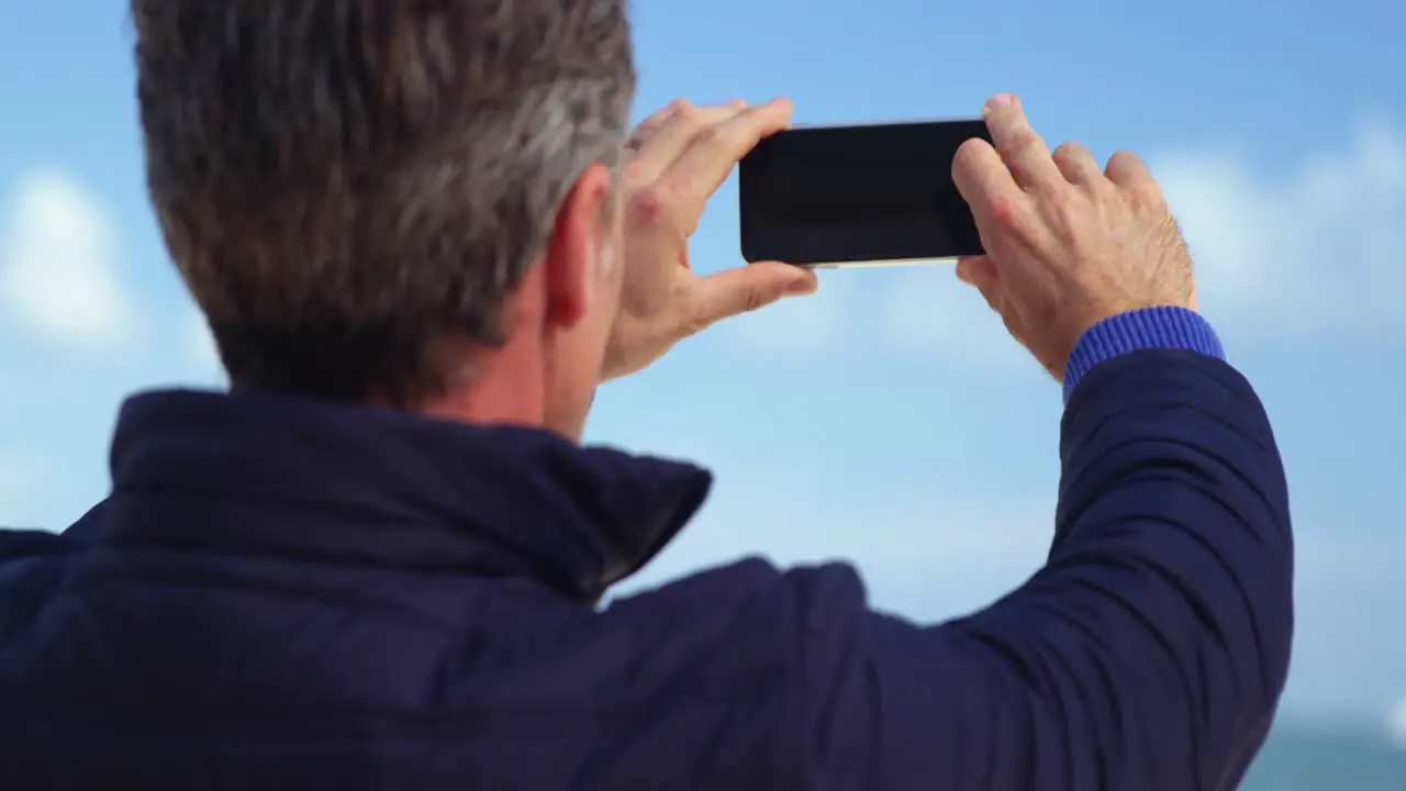 Mature man taking picture of view from mobile phone