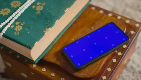 Copy Of The Quran On Stand At Home With Prayer Beads With Blue Screen Mobile Phone