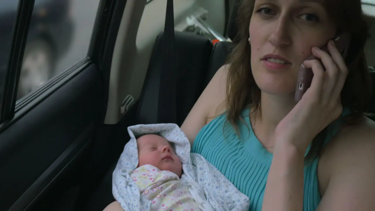 Woman with baby in hands talking on phone