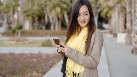 Happy young woman sending a text message