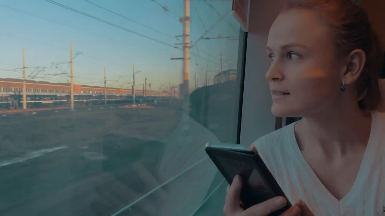 In Saint-Petersburg Russia in train rides young girl and looking out the window holding a cell phone