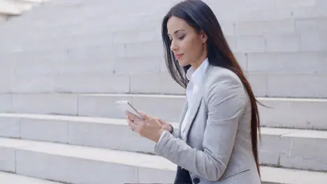 Pretty young worker sitting on steps with phone