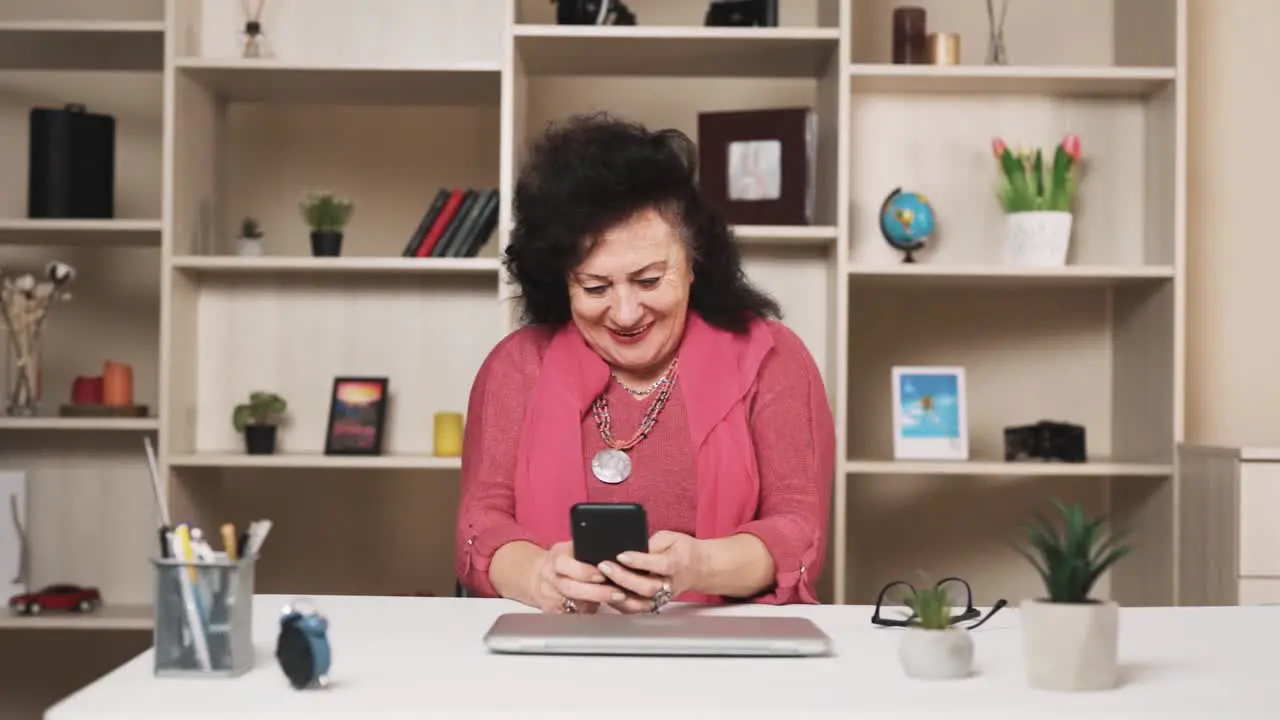 old woman plays a mobile game on a smartphone with enthusiasm and a smile