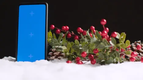 Blue Screen Mobile Phone On Christmas Background With Snow And Foliage 1