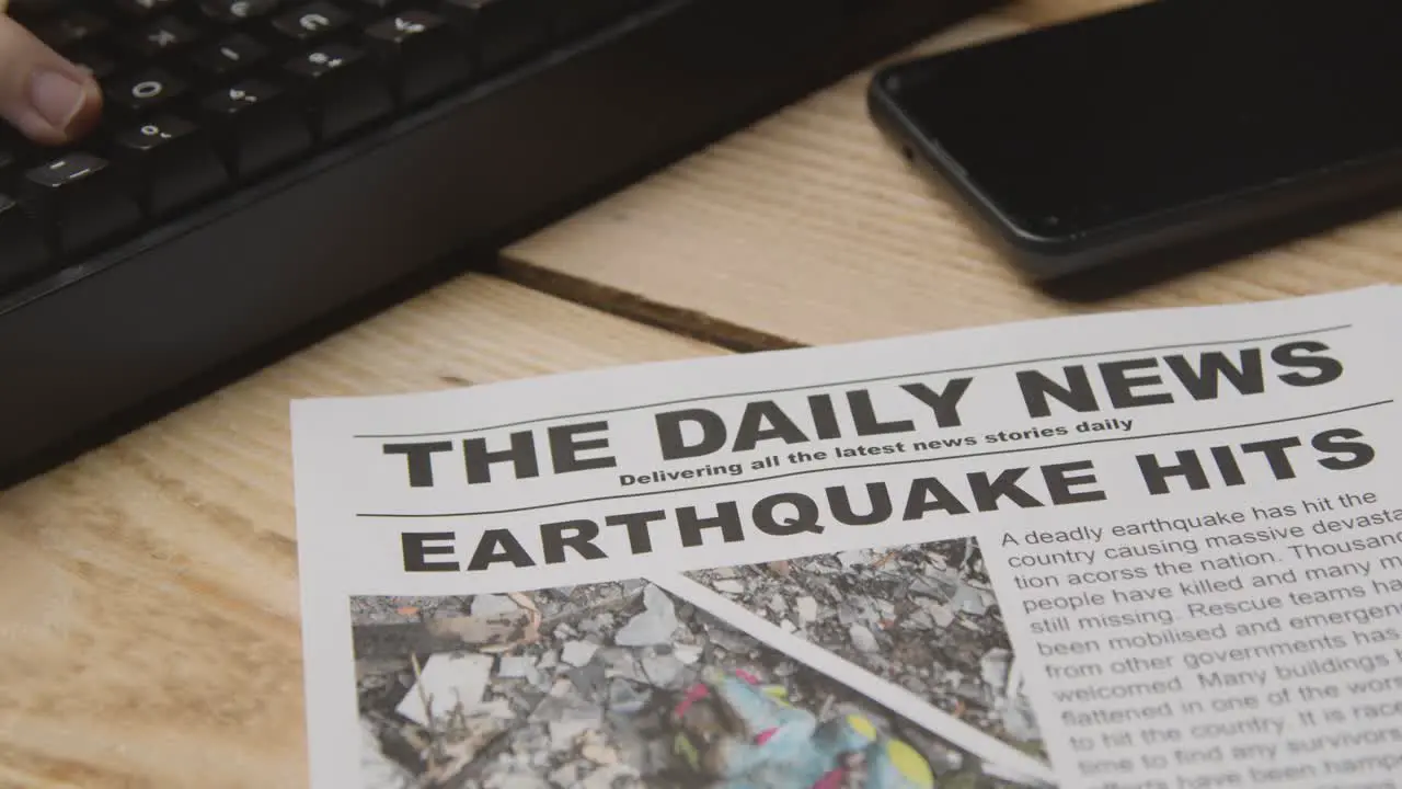 Newspaper Headline Featuring Devastation Caused By Earthquake Disaster On Desk Next To Computer Keyboard And Phone