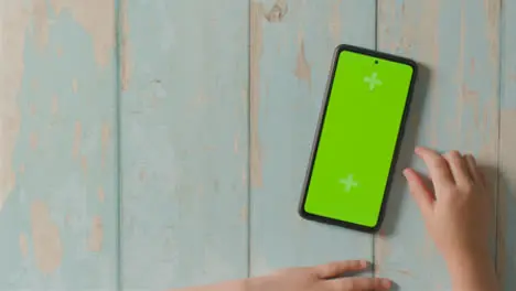 Overhead Studio Shot Of Child Swiping On Green Screen Mobile Phone