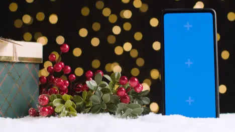 Blue Screen Mobile Phone On Christmas Background With Snow And Gift