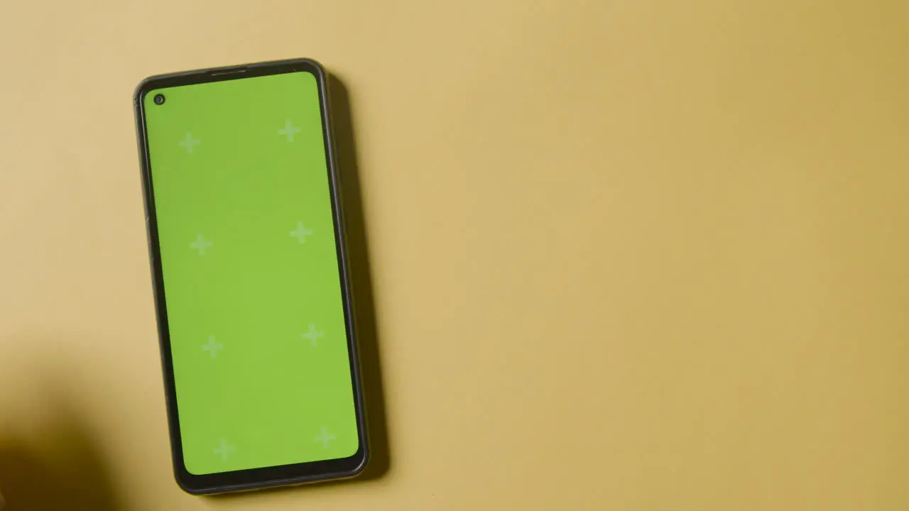 Studio Overhead Shot Of Person Using Green Screen Mobile Phone On Yellow Background 1