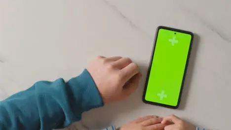 Overhead Studio Shot Of Child Using Green Screen Mobile Phone 6