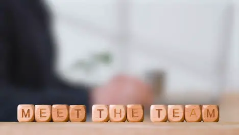 Business Concept Wooden Letter Cubes Or Dice Spelling Meet The Team With Office Person Using Mobile Phone In Background