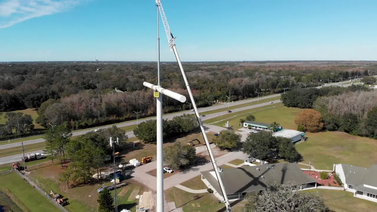 Crane Holding Technicians Installing Cross-shaped Cell Phone Tower