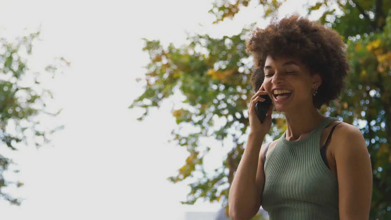 Smiling Young Woman Outdoors Laughing As She Talks On Mobile Phone