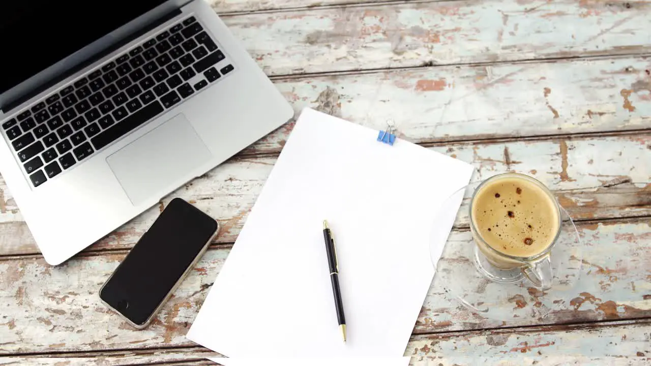 Coffee cup laptop mobile phone clipboard pen on wooden plank