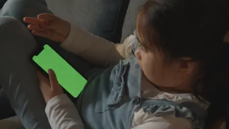 Young Girl At Home Relaxing On Sofa Looking At Green Screen Mobile Phone 1