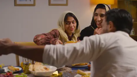 Muslim Muslim Family Sitting Around Table At Home With Food For Meal Celebrating Eid Posing For Selfie 2