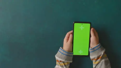 Overhead Studio Shot Of Child Using Green Screen Mobile Phone 4