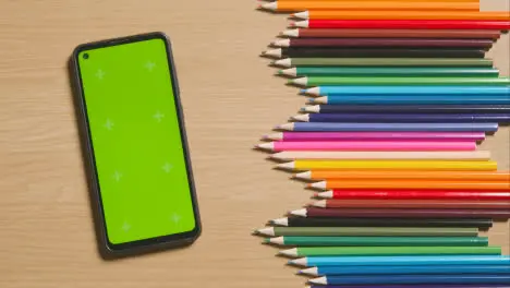 Coloured Pencils In A Line On Wooden Background With Person Choosing Pink One And Green Screen Mobile Phone