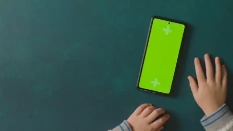 Overhead Studio Shot Of Child Using Green Screen Mobile Phone 3