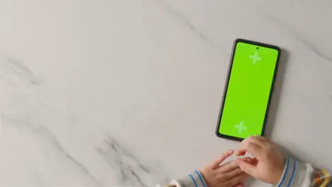 Overhead Studio Shot Of Child Using Green Screen Mobile Phone 5