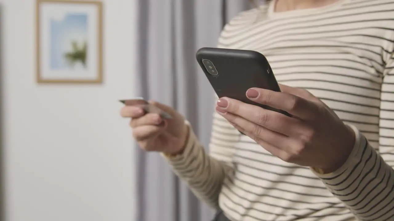 Close Up Of Woman At Home Shopping Online With Credit Card Using Mobile Phone