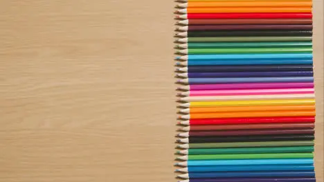 Coloured Pencils In A Line On Wooden Background With Person Putting Down Green Screen Mobile Phone