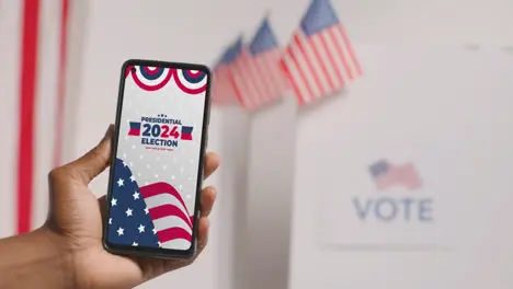 Close Up Of Hand Holding Mobile Phone With Screen Encouraging People To Vote In 2024 US Presidential Election