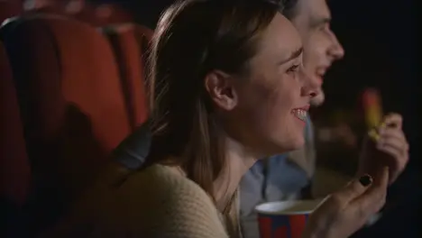 Young couple enjoying film in cinema Couple eating popcorn and watching movie