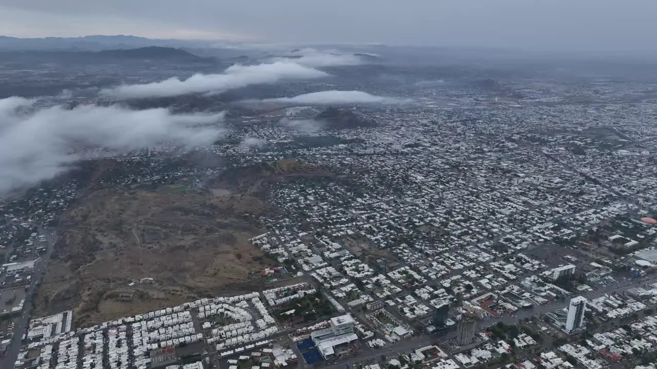 aerial drone shot above the clouds of a small town on cloudy day