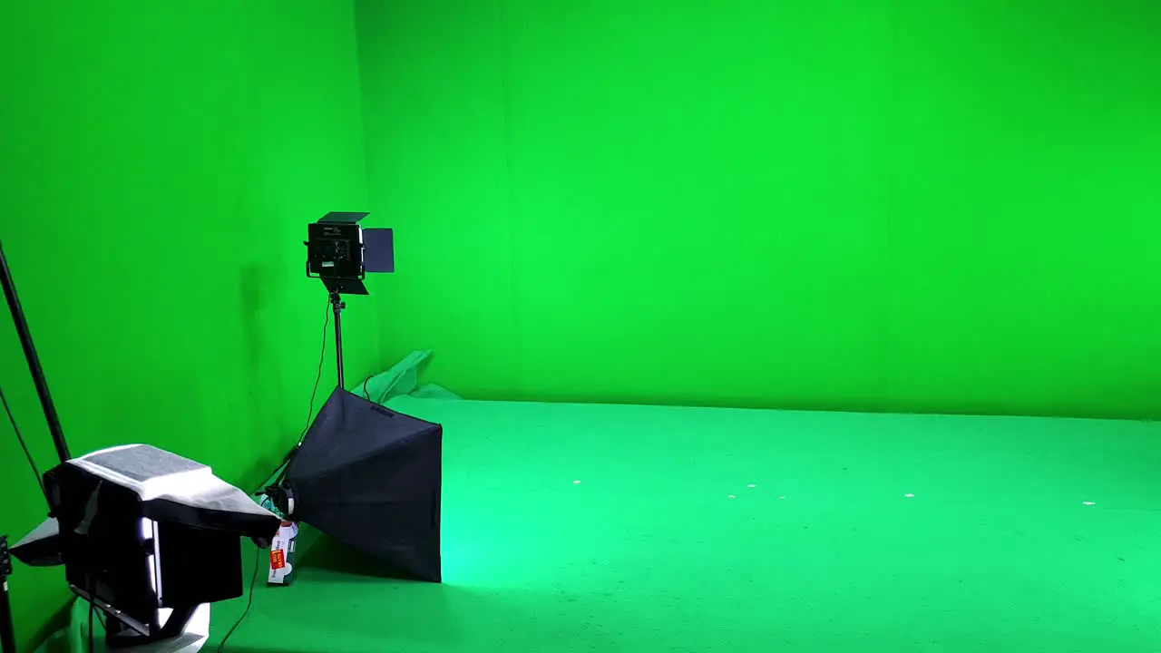 A filming studio simple setup with green screen walls and floor lighting and softbox equipment ready for a video shoot session