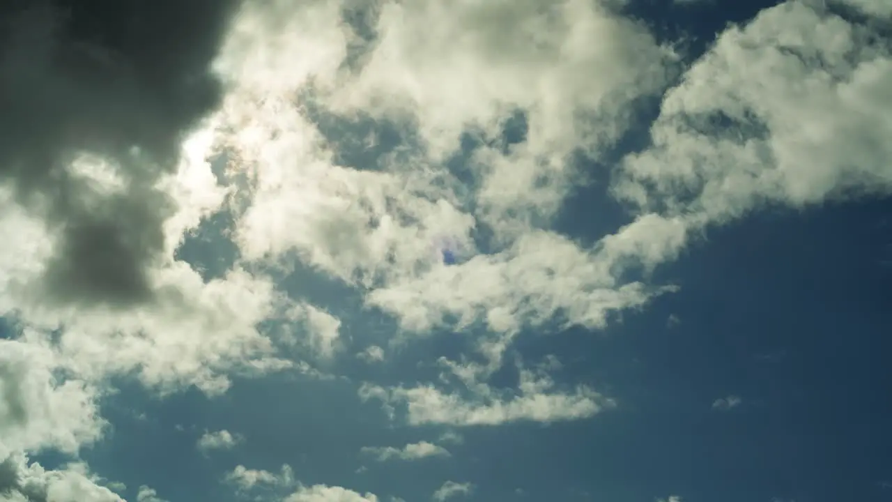 4K timelapse of a sunny blue sky with clouds passing by in front of the sun