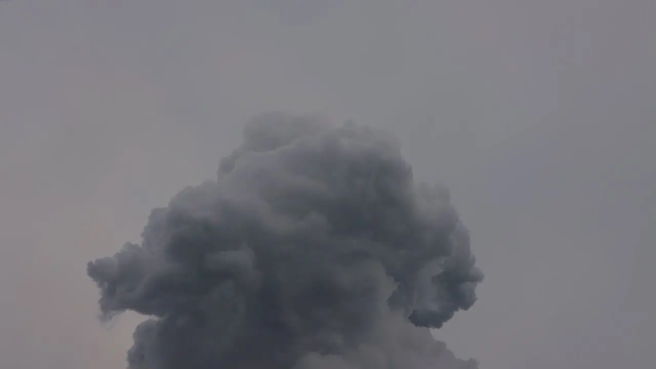 Industrial black hot smoke pushed into the air on a cloudy grey day