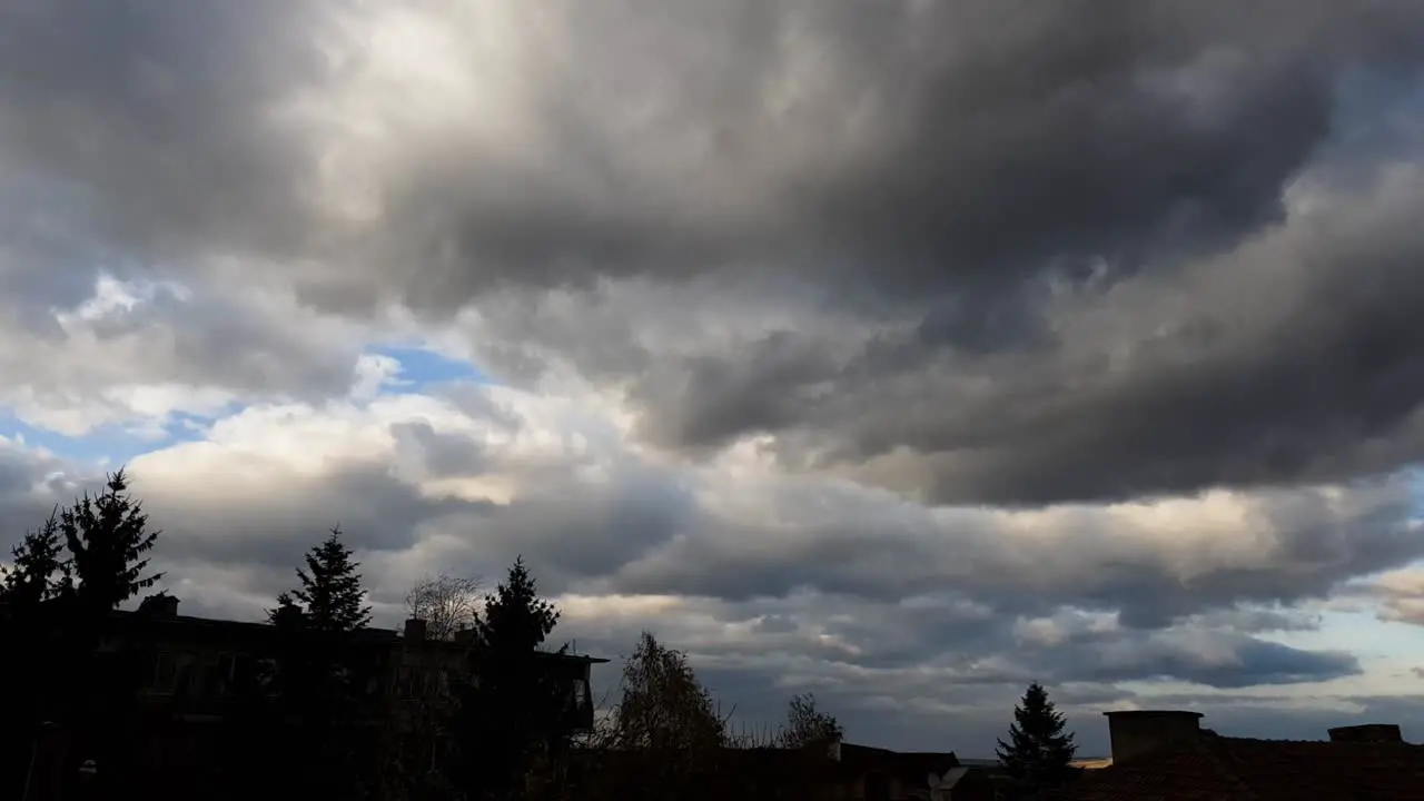 Dark Clouds Blown By The Wind Over House Buildings And Trees low angle time lapse