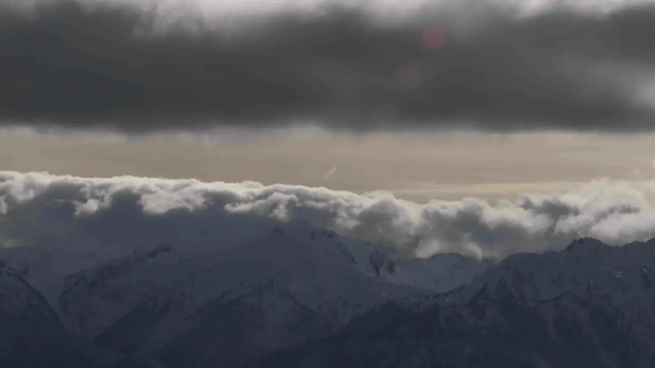 A beautiful time lapse shot of fog and clouds rolling over the top of a mountain range