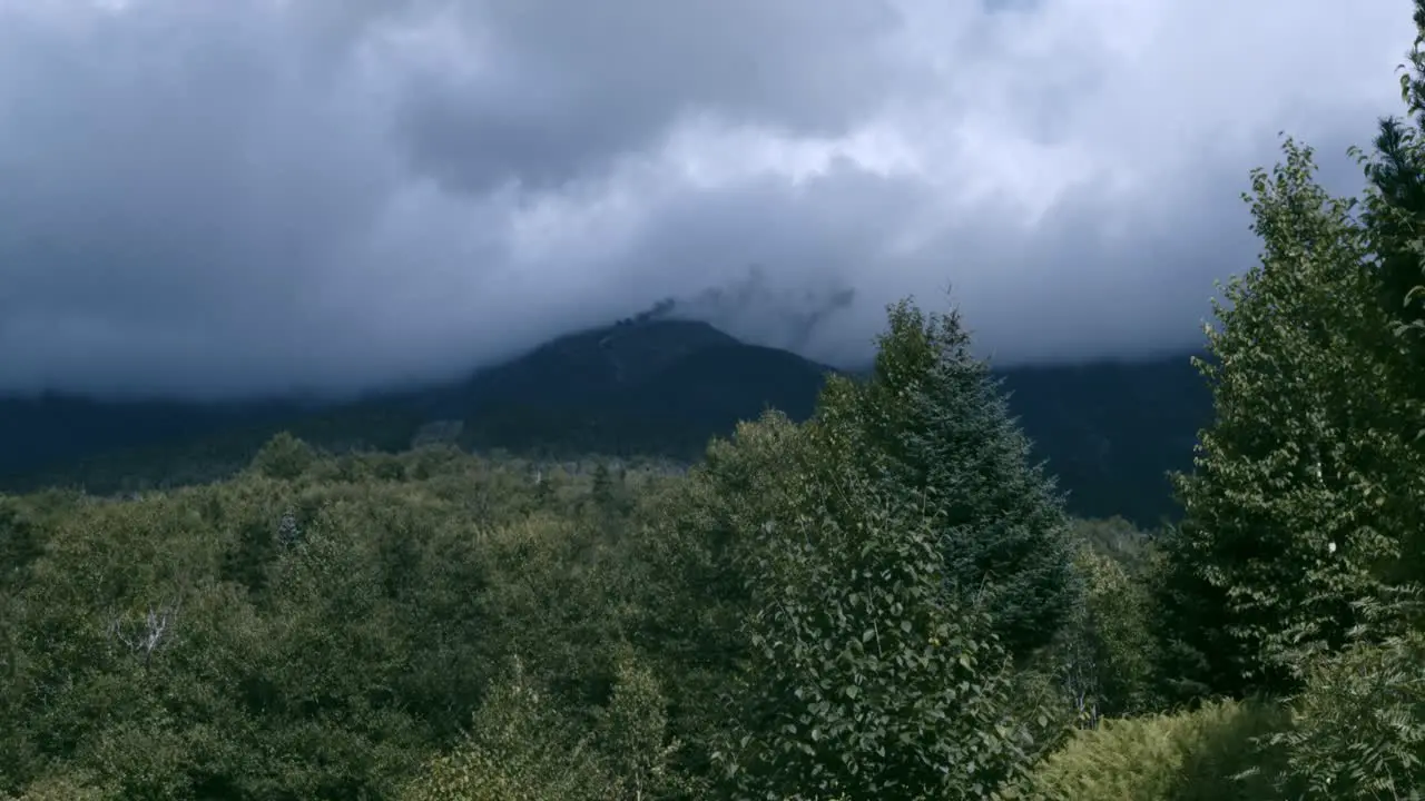 Dark clouds rest on Mount Washington as smoke from the cog railway is visible