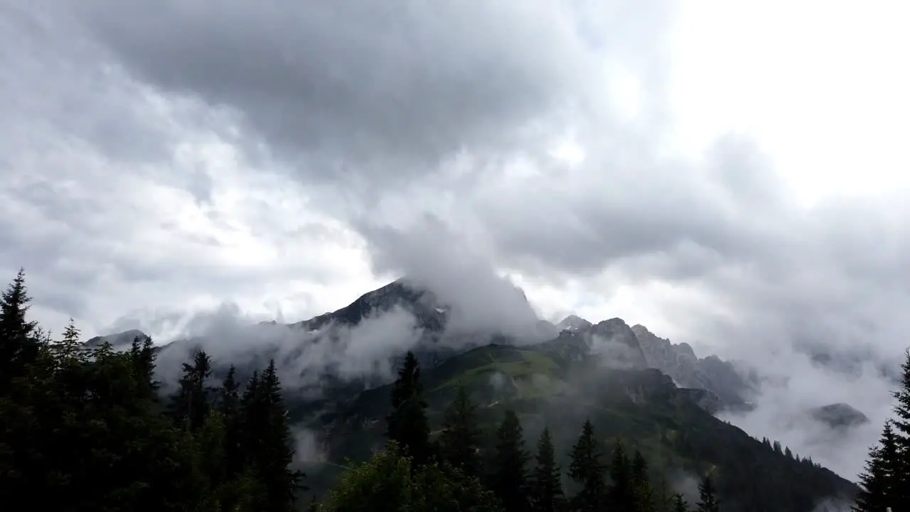 Timelapse pan left to right showing the mountain Alpsitze of german alps with many clouds wrapping around during evening time after a heavy storm