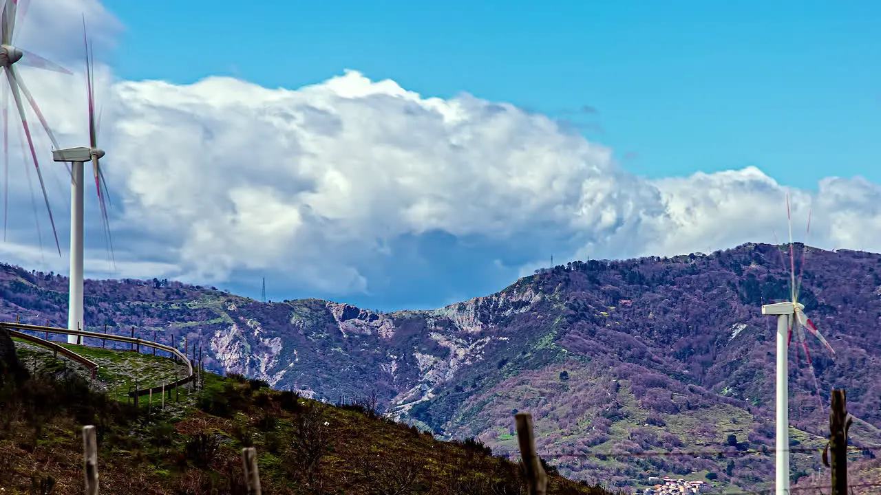 Time lapse of spinning wind turbine farm on hills and clouds passing quickly