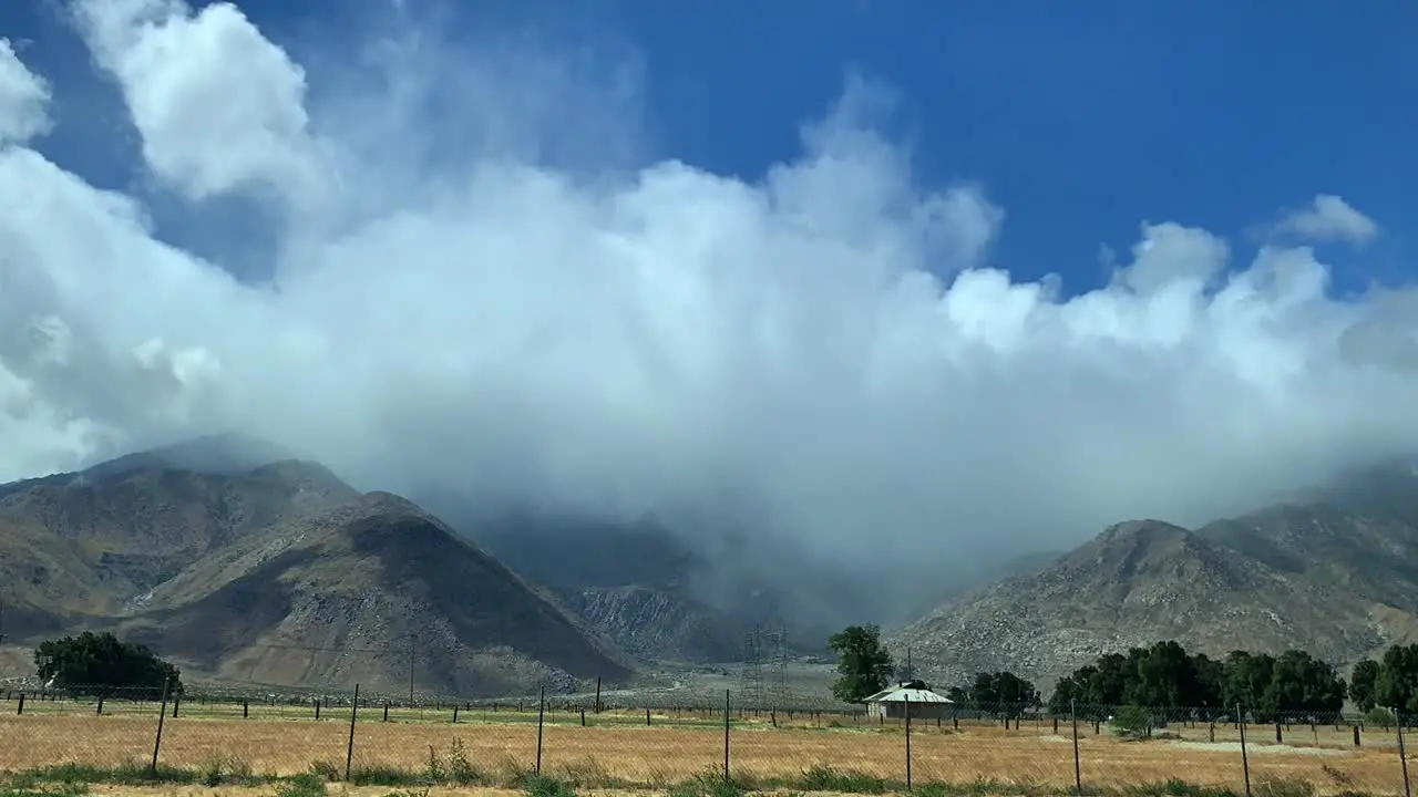 4k timelapse rural mountain landscape with blowing clouds dramatically flowing through a blue sky and over the mountain