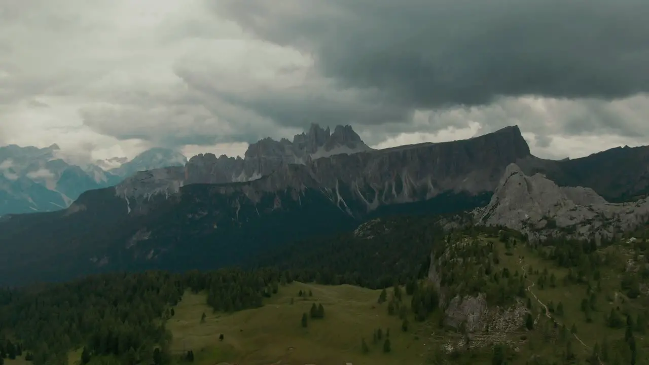 Aerial view with distant steep tall mountains in the background green forest with valley between mountains before storm rainy day cinematic grade