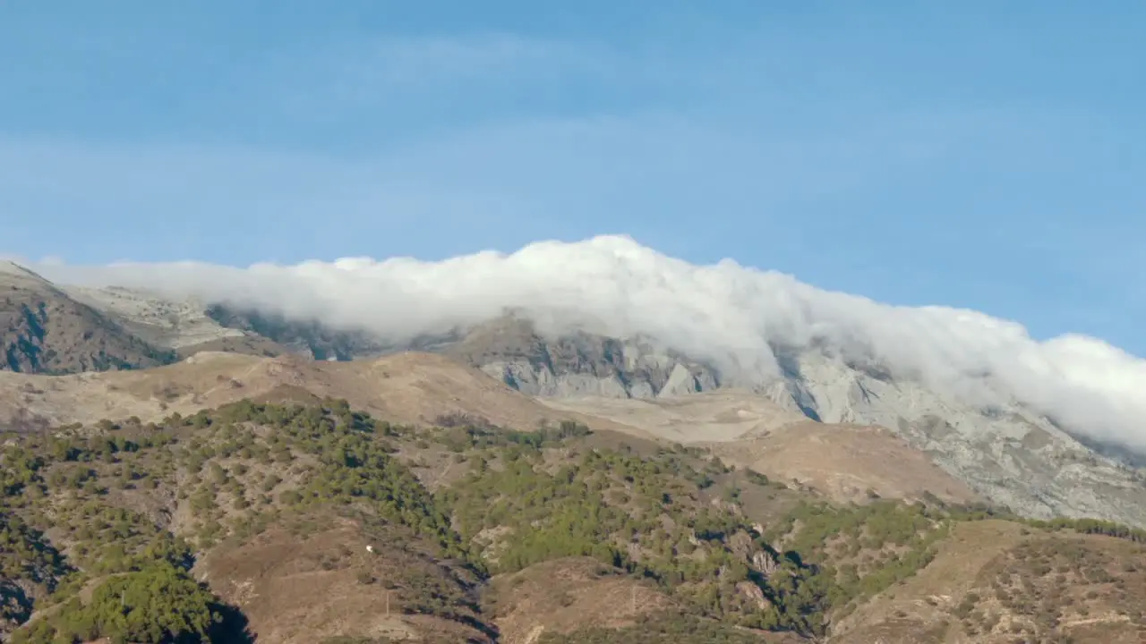 Timelapse of Billowing Clouds Rolling Over the Top of a Mountain