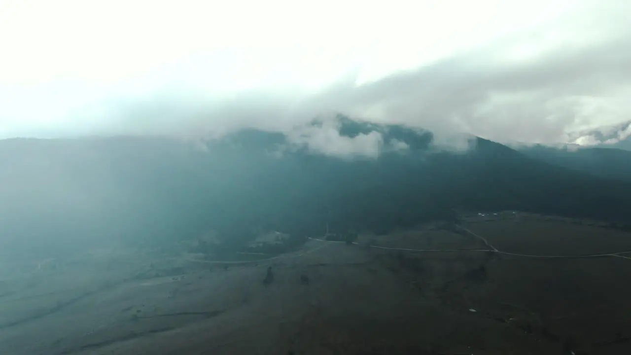 Drone shot of a field and мountain with cloudy sky