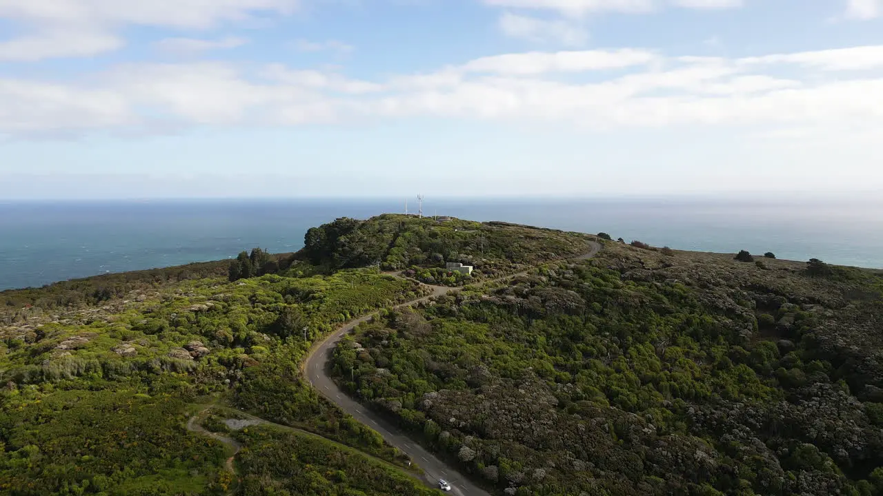 Aerial drone tilt up shot over a beautiful hilltop viewpoint with the view of Bluff Beach and sea in the background in North Island New Zealand