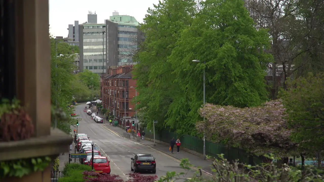 A cloudy winter day in Glasgow West End with buildings trees cars and people walking