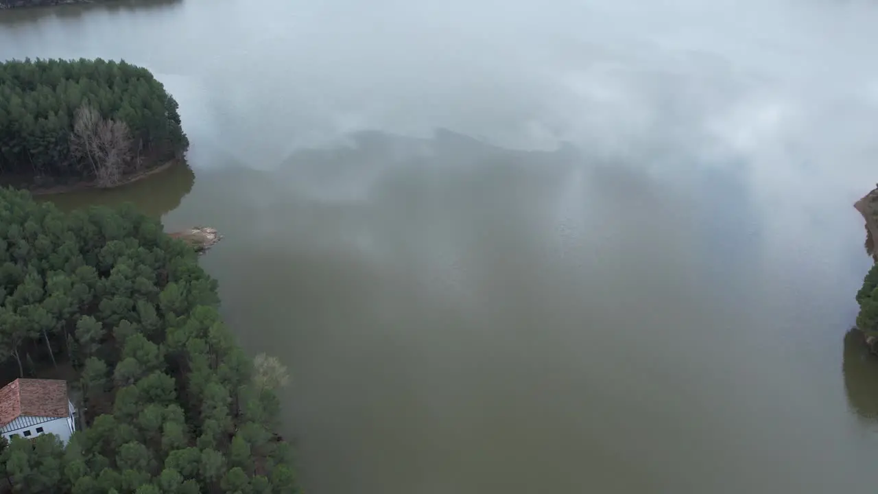 Aerial drone view of a medium size dam and a reservoir in a cludy day over mirrow water in Castellon Spain