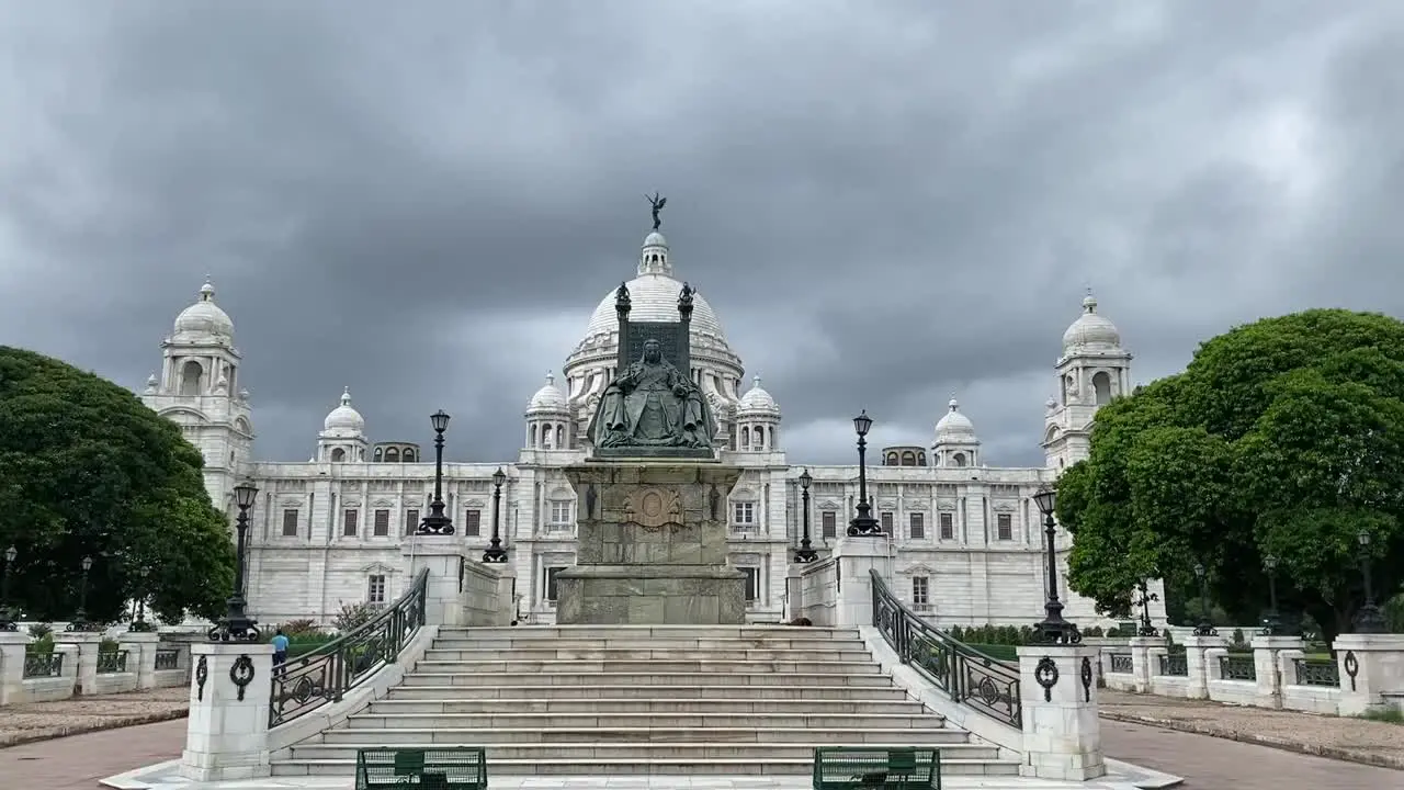 Static shot of marble stairways leading up to Queen Victoria sitting in front of Victoria Memorial in Kolkata India on a cloudy day