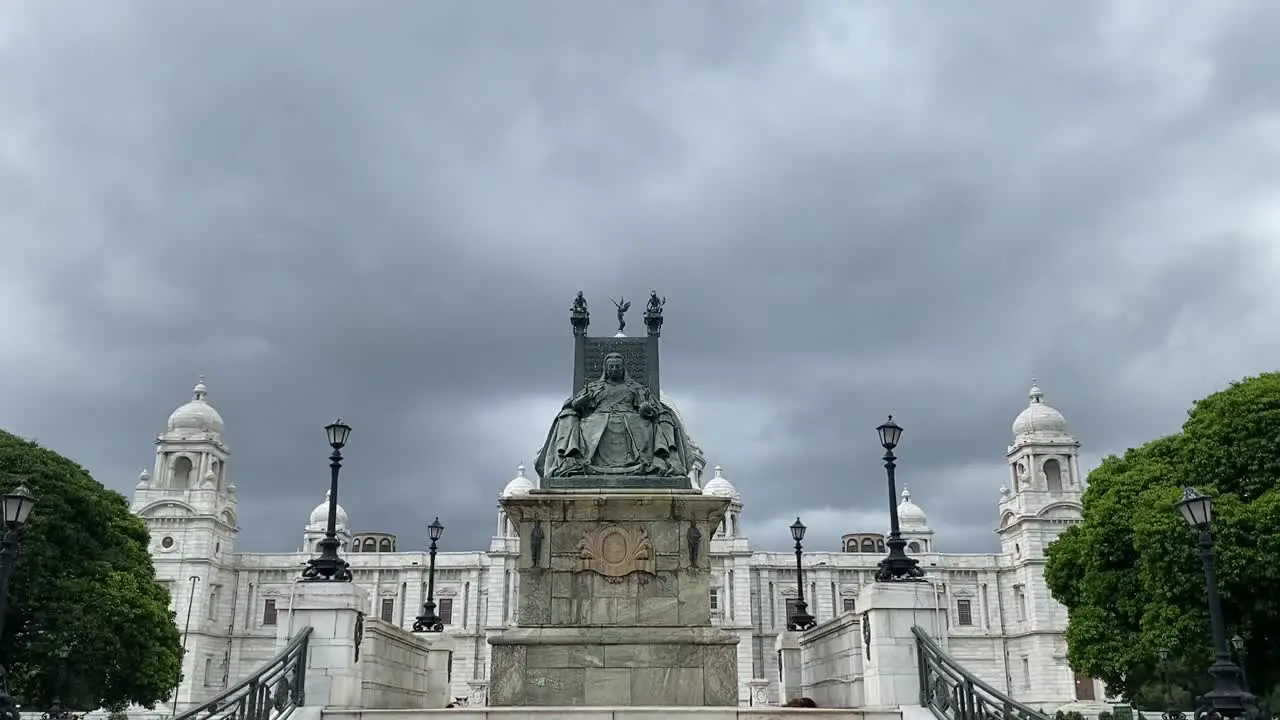 Tilt up shot of entrance stairs leading up to the statue of Queen Victoria sitting in front of Victoria Memorial in Kolkata India on a cloudy day