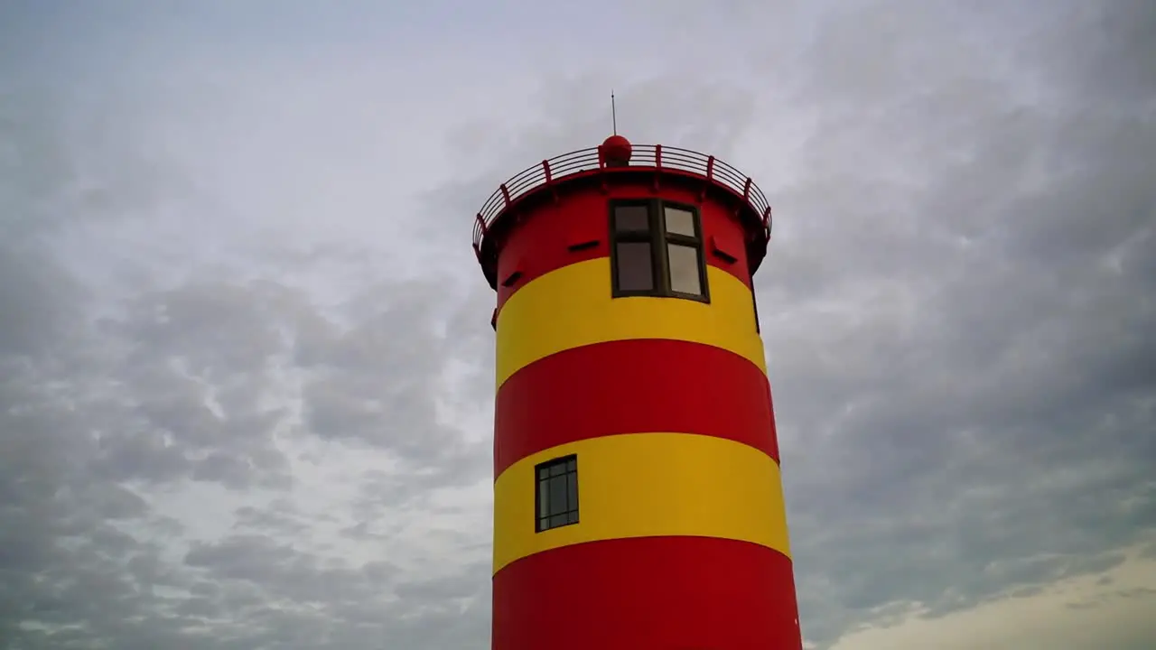 Red yellow small Otto Waalkes lighthouse in front of an overcast sky with thick clouds in the evening