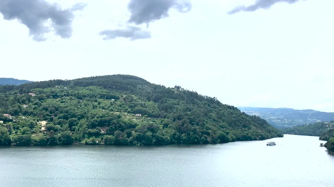 Ferry bringing tourists who are enjoying the moment on the Douro River on a cloudy day in calm and tranquil waters