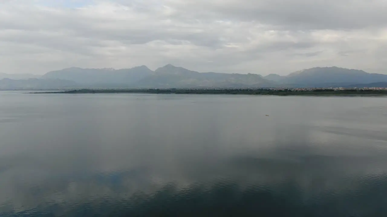 Drone view in Albania flying over Shkodër lake in Pogradec on cloudy day with mountains in the horizon