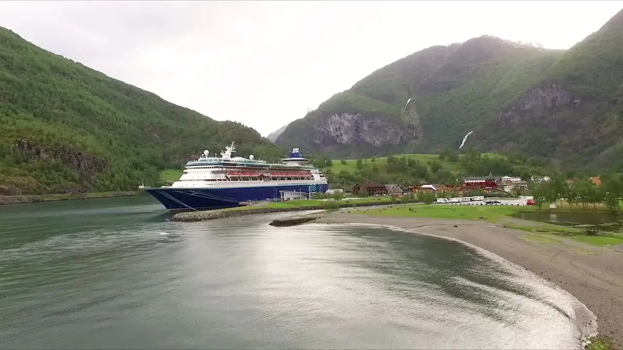 Beautiful drone shot flying low towards a docked cruise ship in Flam Norway